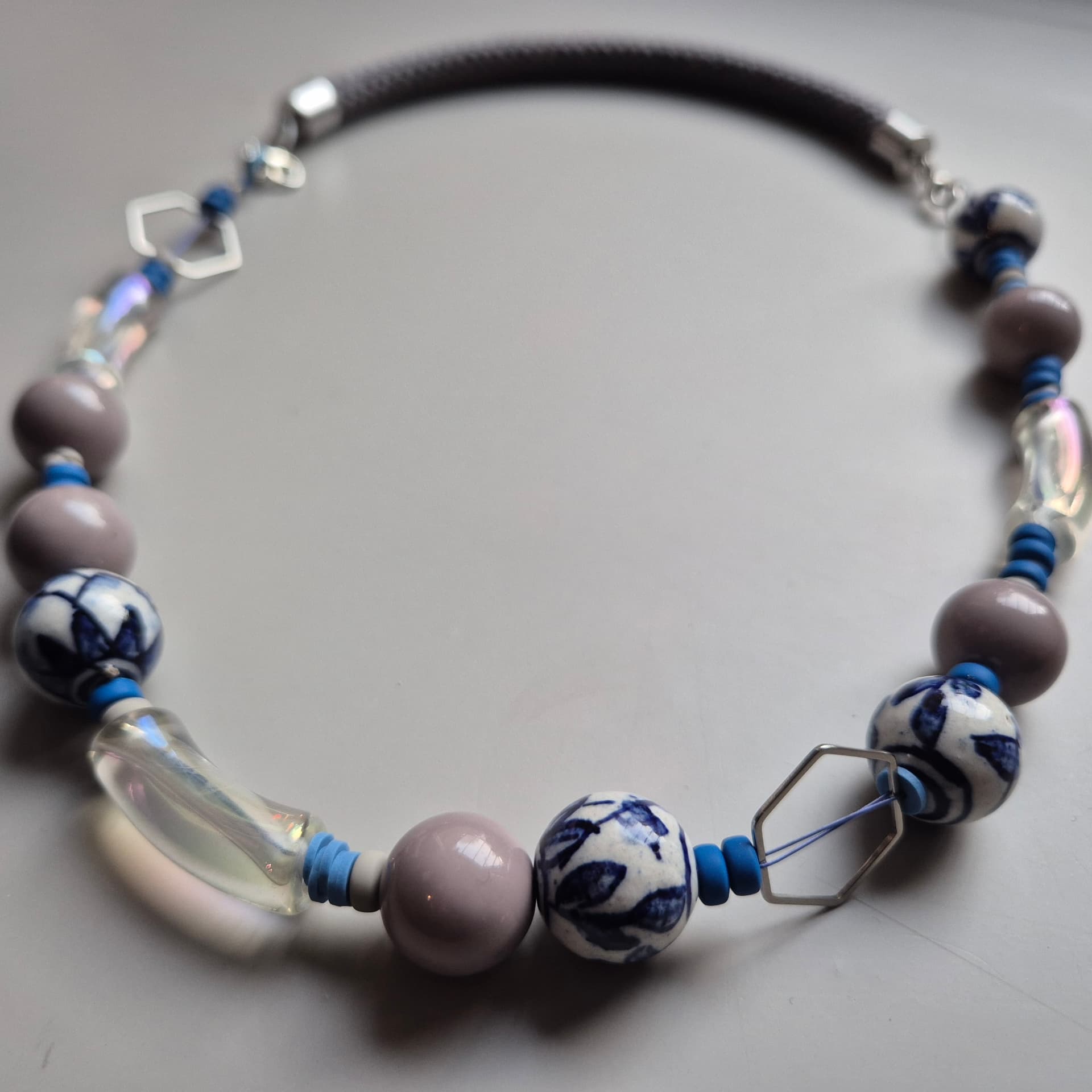 Necklace of blue-and-white painted porcelain beads, iridescent glass and mauve ceramic on a brown rope
