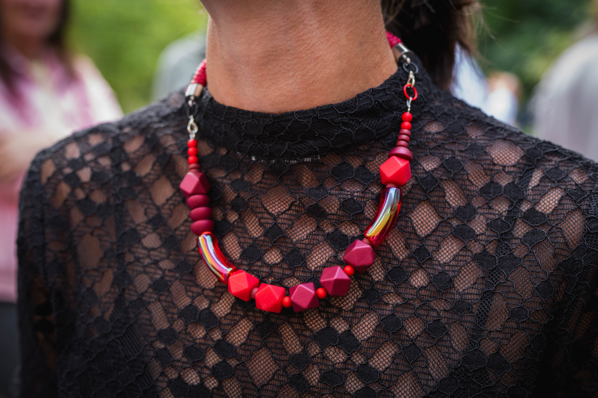 Red necklace with berry and scarlet faceted beads, iridescent red glass tubes and red rope worn against black lace