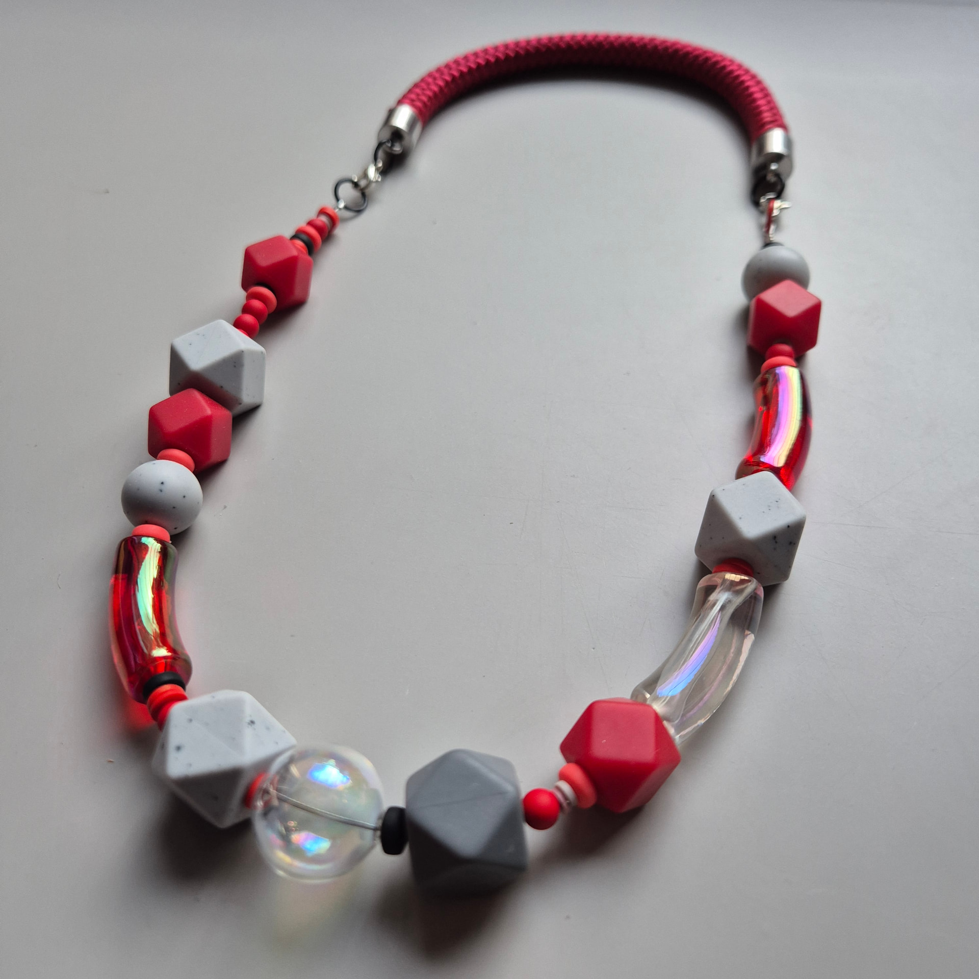 Necklace with red faceted beads, speckled grey stone facets and iridescent glass on a red rope