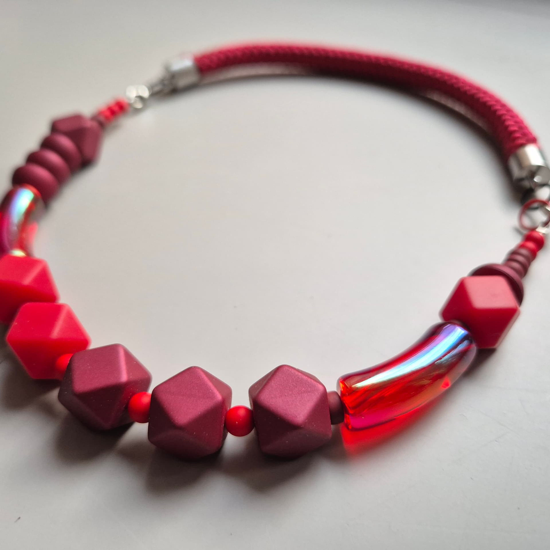 Necklace of berry and scarlet faceted beads with an iridescent red glass tube on a red rope