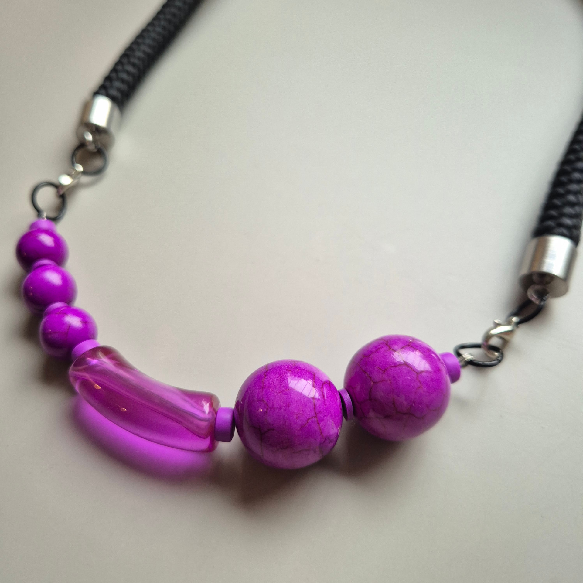 Necklace with fuchsia spheres, crackled spheres and curved transparent glass on a black rope