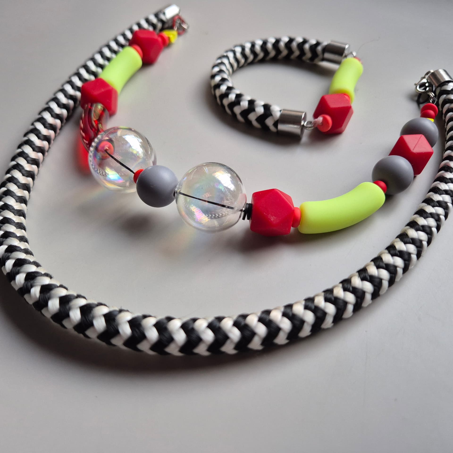 Necklace and bracelet set with neon yellow tubes, red faceted beads and iridescent bubble glass on chevron rope